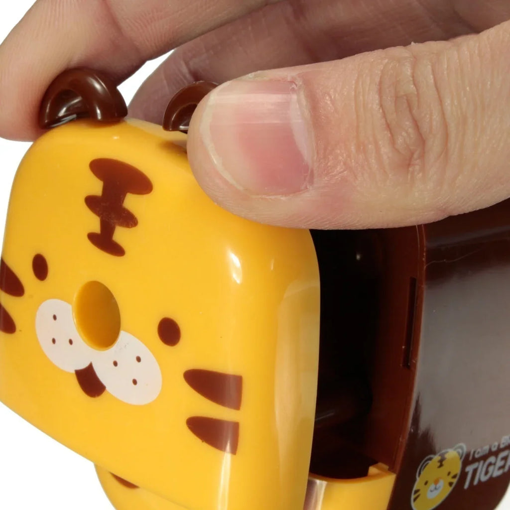 Hand inserting pencil into tiger animal pencil sharpener