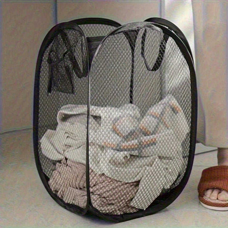Black collapsible laundry hamper with mesh panels holding folded clothes