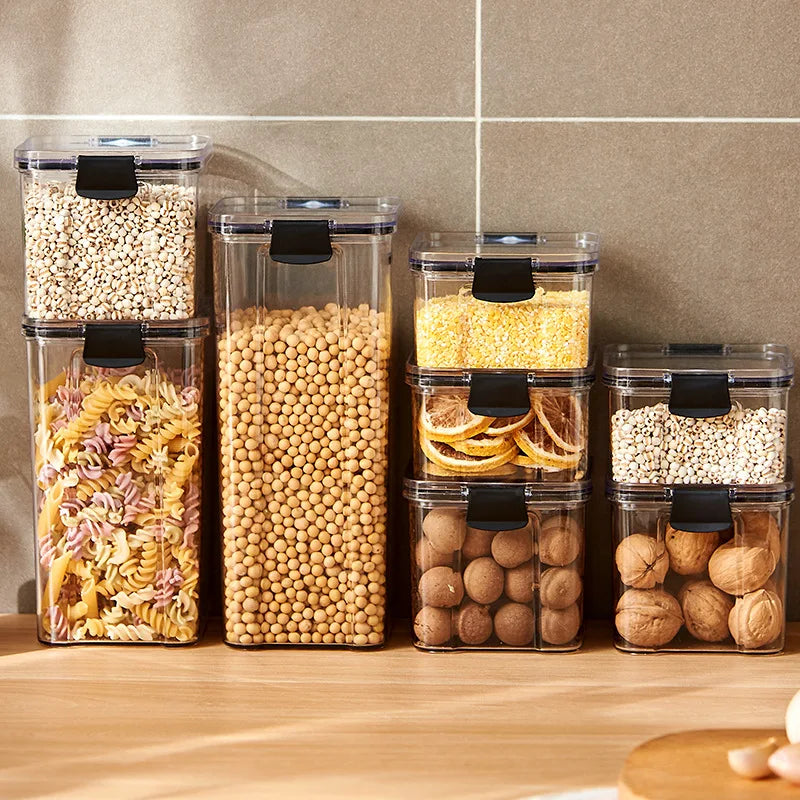 Set of clear kitchen storage jars with black airtight lids holding grains and pasta
