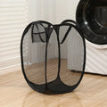 Black collapsible laundry hamper standing empty in a laundry room