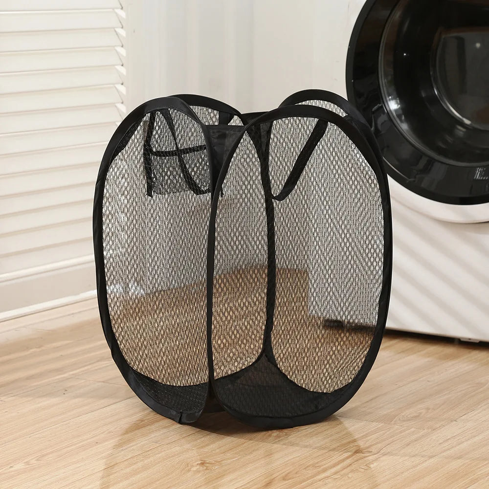 Black collapsible laundry hamper standing empty in a laundry room