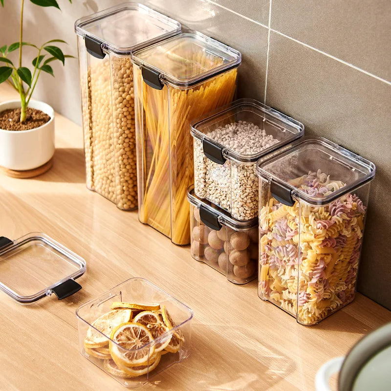 Airtight kitchen storage jars with pasta, grains and snacks on a wooden counter