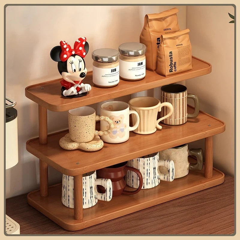3-tier bamboo coffee mug holder stand with mugs, jars and coffee bags on a kitchen counter